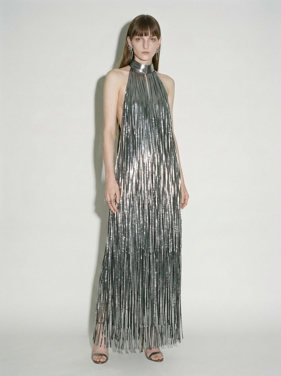 Woman wearing silver liquid fringe halter maxi dress with open back.